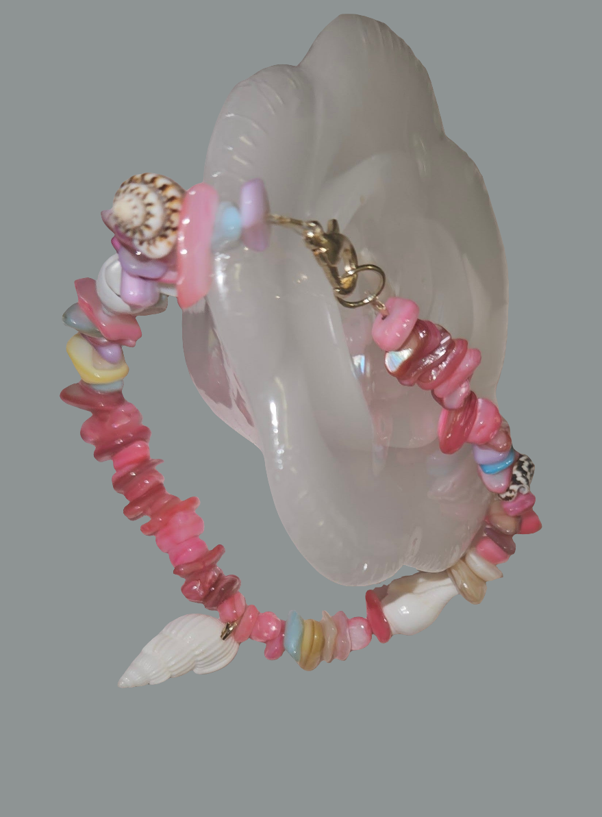 Pink beaded bracelet with shell elements on a gray background