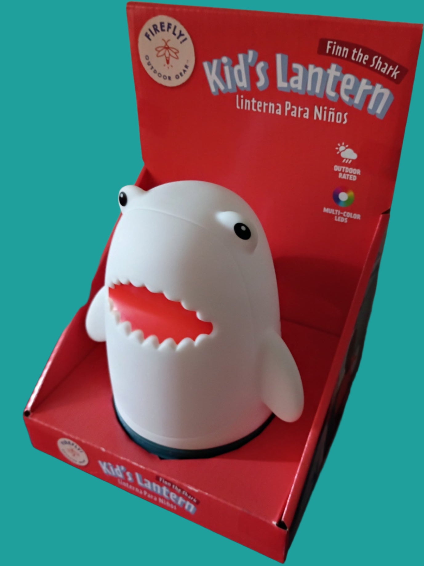 Shark-shaped kids' lantern in a red box on a red surface with a white wall background.