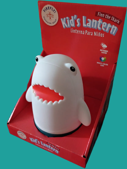 Shark-shaped kids' lantern in a red box on a red surface with a white wall background.